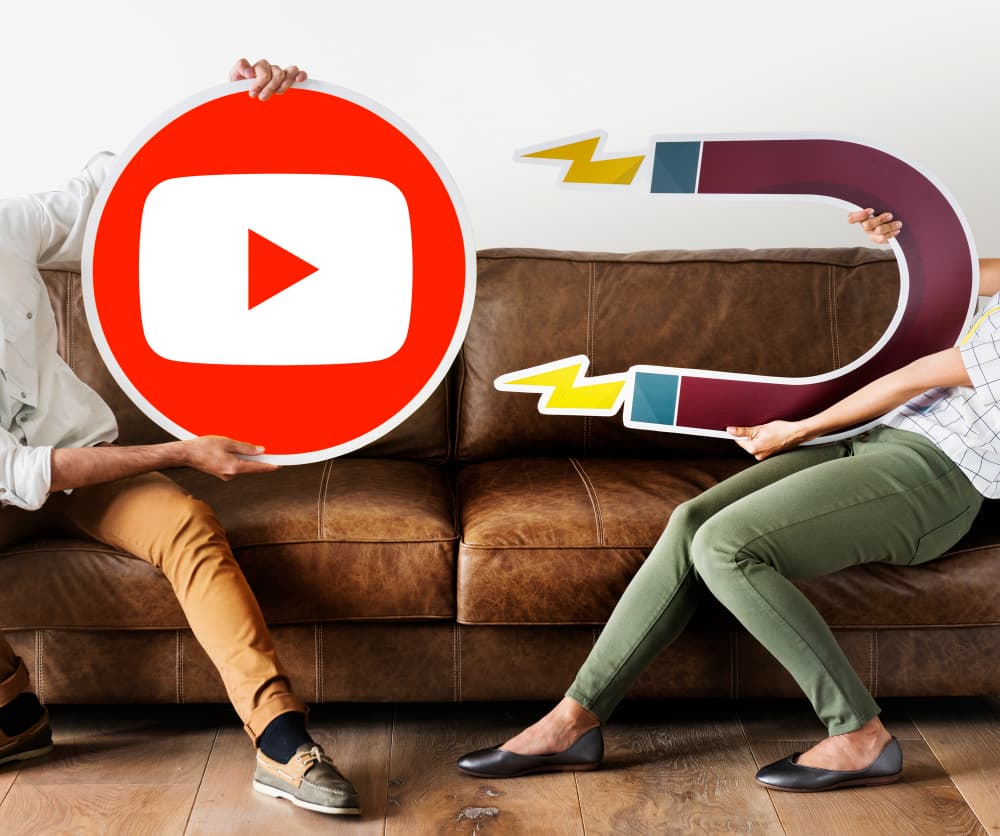 Two people holding a YouTube play-button icon and a magnet